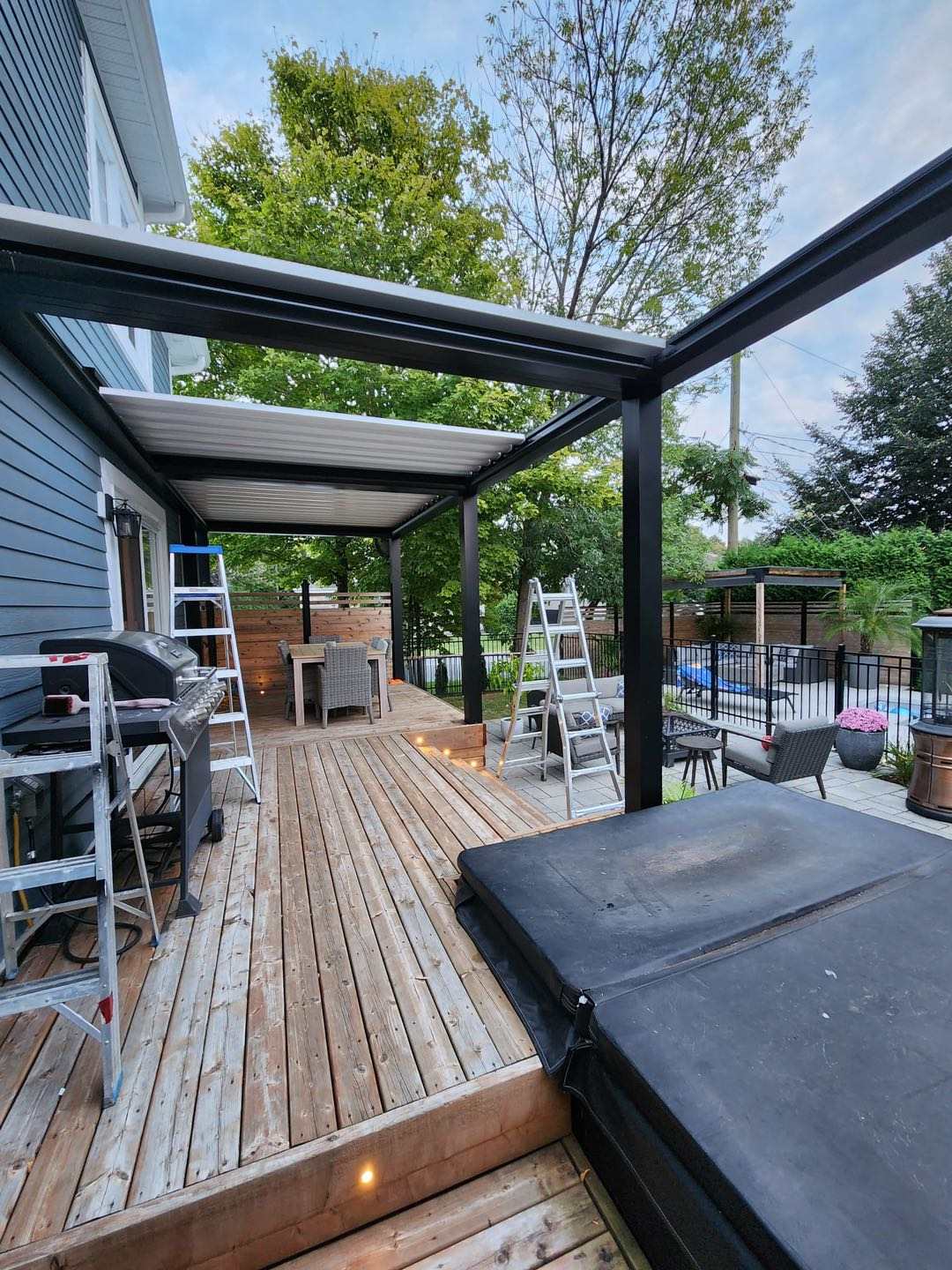 Louvered pergola attached to home over wood deck