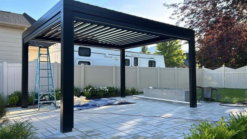 Freestanding black louvered pergola on paver patio